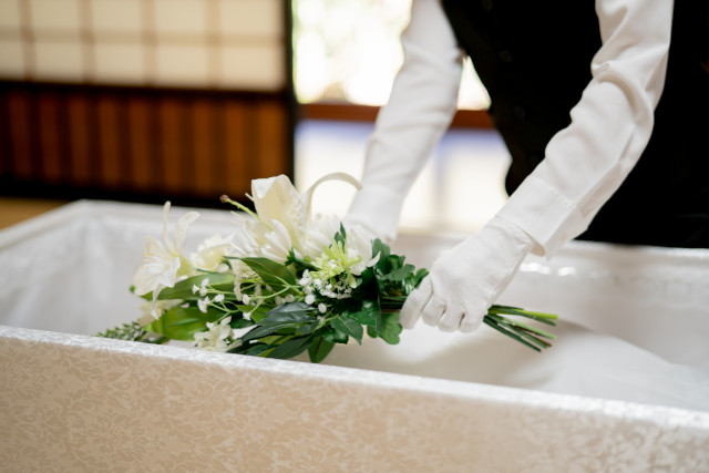 棺に花を入れる葬儀会社スタッフ